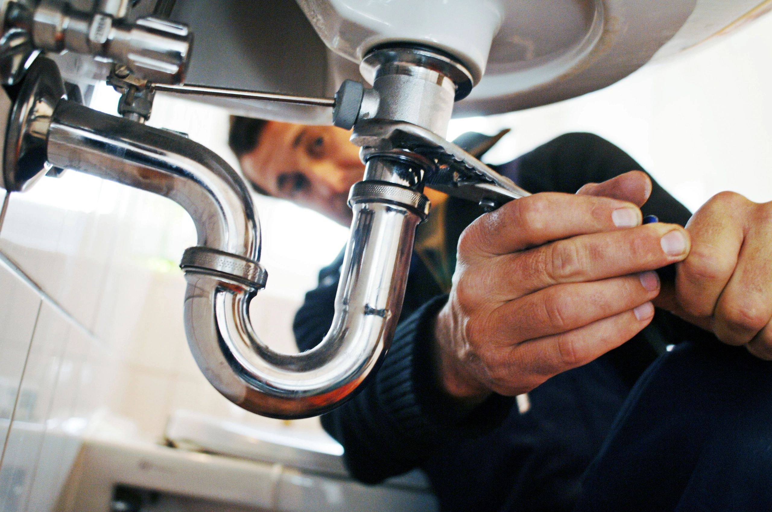Hands working on chrome sink pipes